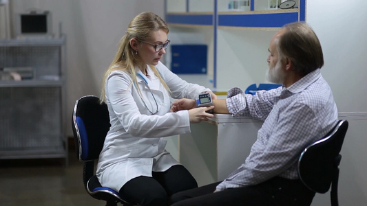 金发女性医生对老年人进行血压测试视频