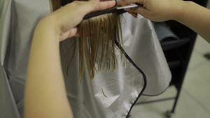 理发师用剪刀和梳子给金发女人理发后视图特写镜头20秒视频