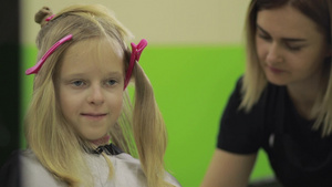 可爱的女孩在理发店由专业发型师理发15秒视频