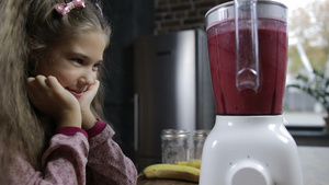 微笑的小女孩看着搅拌机里的健康浆果冰沙混合22秒视频