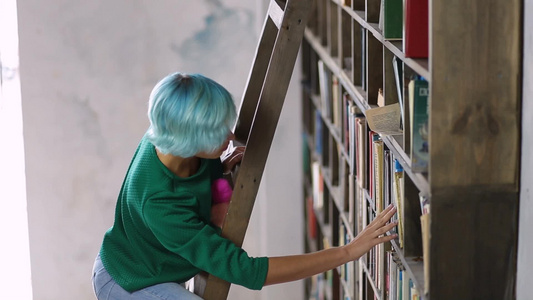 女学生戴着眼镜在图书馆的书架上寻找书视频