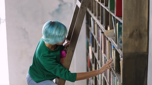 女学生戴着眼镜在图书馆的书架上寻找书26秒视频