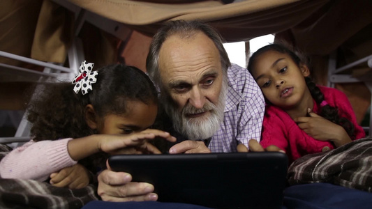 漂亮的孩子教他们英俊的祖父使用平版视频