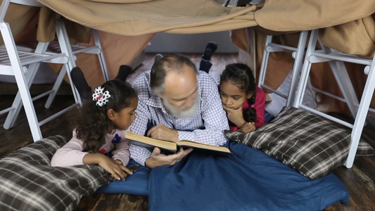 深情英俊的祖父与可爱孙女们在床上读圣经并讲解视频