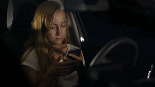 金色长发女人坐在车里玩手机视频