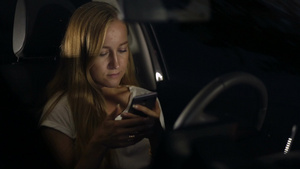 金色长发女人坐在车里玩手机14秒视频