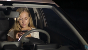 夜晚金色长发女人坐在车里使用智能手机上网11秒视频