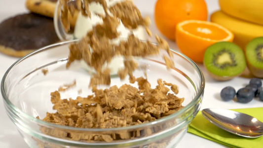 谷物片落在玻璃碗中准备做健康的有机早餐视频