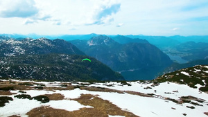 阿尔卑斯山奥地利雪山绿色降落伞飞行滑翔伞的空中全景17秒视频