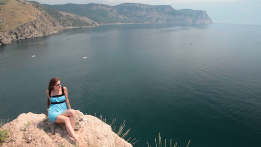 年轻的女人坐在黑海附近的悬崖上视频