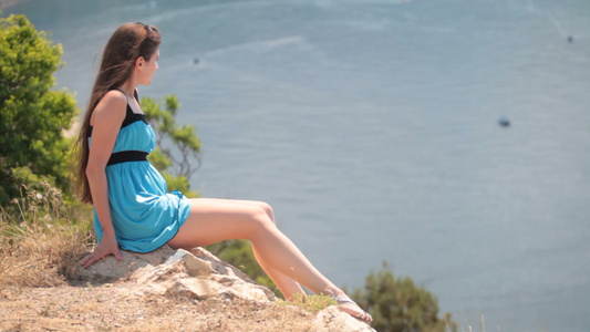 年轻的女人坐在海边悬崖视频