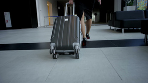 商务妇女穿着正式的衣服带着一个带轮子的袋子在机场楼11秒视频