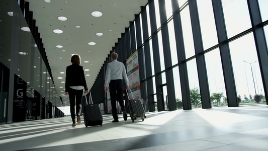 商务人士拉着行李箱穿梭在机场大楼中视频