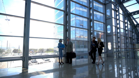商务人士行走在现代玻璃办公楼大厅视频