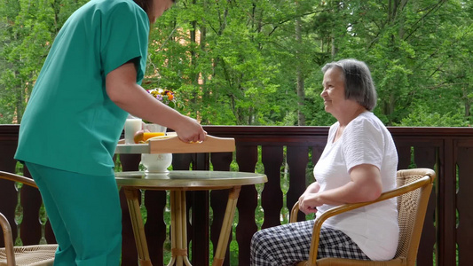 微笑的护士在养老院为老年妇女提供早餐视频