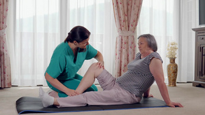 护士在养老院给老年妇女做腿部康复训练和按摩19秒视频