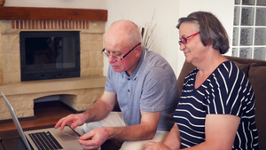 老年夫妇在笔记本电脑上用信用卡在家购物21秒视频