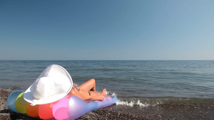 穿着白太阳帽的年轻女人在海滩上晒黑20秒视频