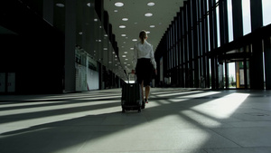 商务妇女拉着行李在机场候机楼行走4秒视频