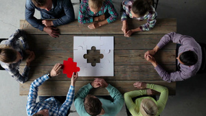 一群工作人员围坐在会议桌前一起完成一张拼图表现团队合作的概念10秒视频