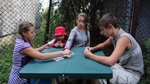 快乐的孩子们玩扑克牌游戏坐在院子里的桌子上20秒视频