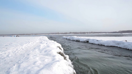 西伯利亚冬天被雪覆盖的河岸和流淌的河水视频