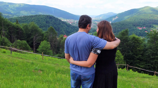 一对夫妇站在山顶拥抱看着美丽的景色视频