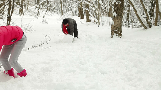 年轻夫妇在雪地上推雪人视频