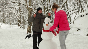 年轻的夫妇在冬天的森林里堆雪人15秒视频