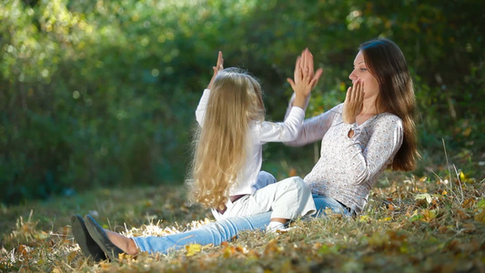 公园里年轻的母亲和女儿一起在草地上玩耍视频