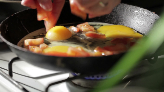 厨师平底锅里煎鸡蛋并加入番茄片视频