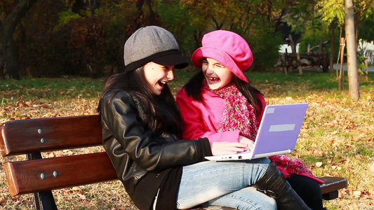 公园里坐在长凳上玩笔记本电脑的两个女孩视频