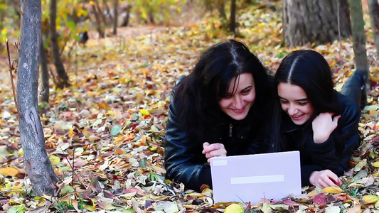 秋天公园内母女俩看笔记本电脑视频