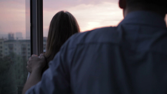 一对年轻夫妇在阳台上看美丽的日落风景[迷人]视频