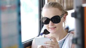 漂亮的年轻女人戴着太阳镜在公共汽车举着手机拍照12秒视频