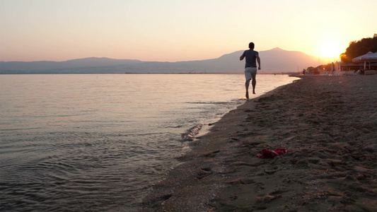 黄昏男子沿着海滩奔跑视频