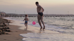 父亲和他的小儿子穿着泳衣在海滩上跑着打闹15秒视频