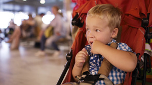 小男孩坐在机场的儿童手推车里20秒视频