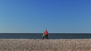 母亲父亲和儿子走在鹅卵石的海滩上17秒视频