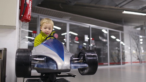 小男孩在购物中心外门口处驾驶一辆高架模型赛车玩具25秒视频