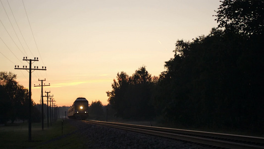 日落时分带着明亮前照灯的旅客列车在乡下慢慢地经过视频
