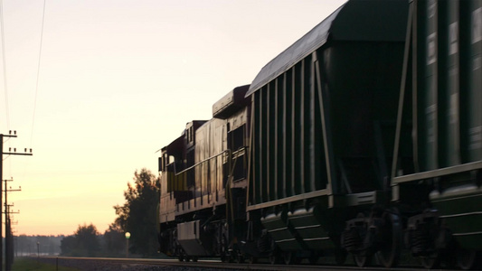 货运火车在日落时在乡下慢慢地靠近又渐渐远去的景色视频