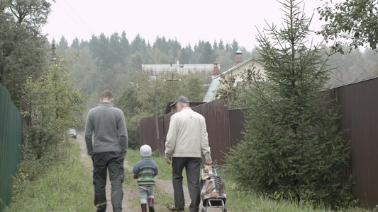 父亲和儿子还有爷爷沿着村子里的路走着视频