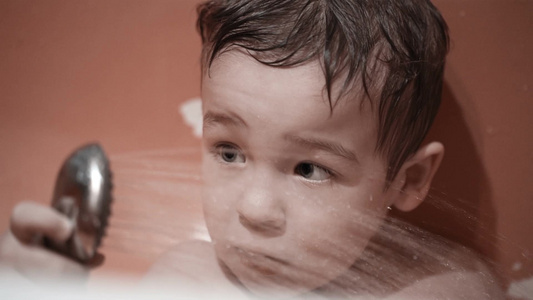 小男孩拿着淋浴看着喷水视频