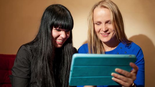 两个年轻女性在开心地阅读平板电脑信息视频