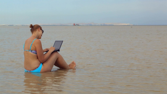 海边的女人在笔记本电脑上打字视频