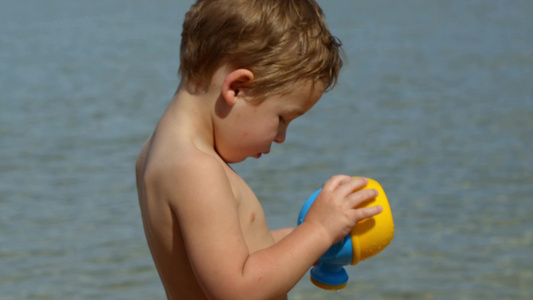 小男孩在海边玩水壶视频