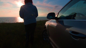 女人离开了汽车在日落时朝海边走去21秒视频