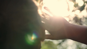 一个女人在日落时看向远方同时用手遮住太阳的特写后景11秒视频