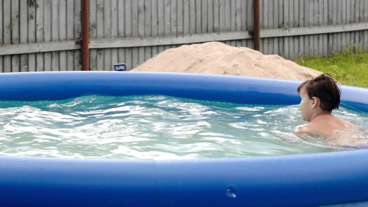一个男孩独自在院子里的充气游泳池游泳视频